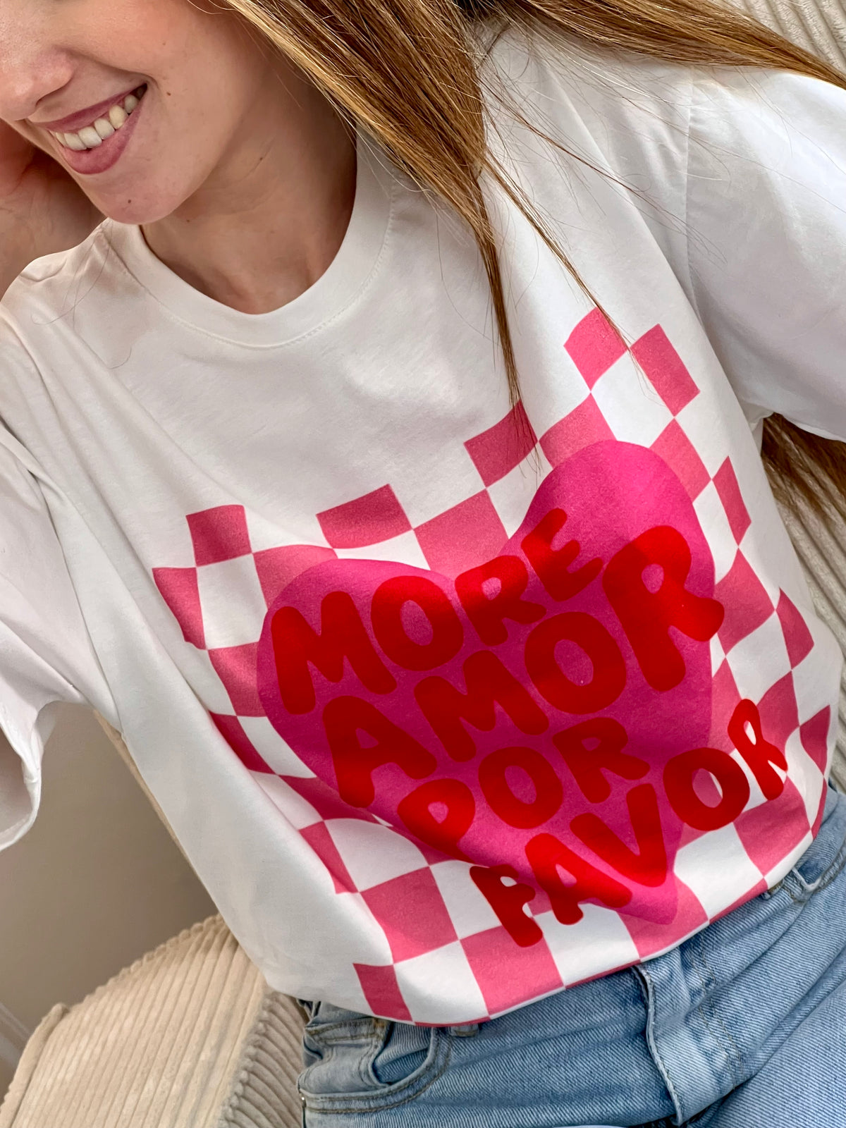 Tee-shirt blanc femme à manches courtes, idéal pour un look tendance et féminin. Doté d’un col V et d’une inscription rose "More Amor Por Favor", il apporte une touche moderne et romantique. Ses motifs cœur et quadrillage ajoutent du style et de l’originalité. Facile à porter au quotidien, ce tee-shirt aux couleurs blanc, rose et rouge est parfait pour une tenue casual chic.