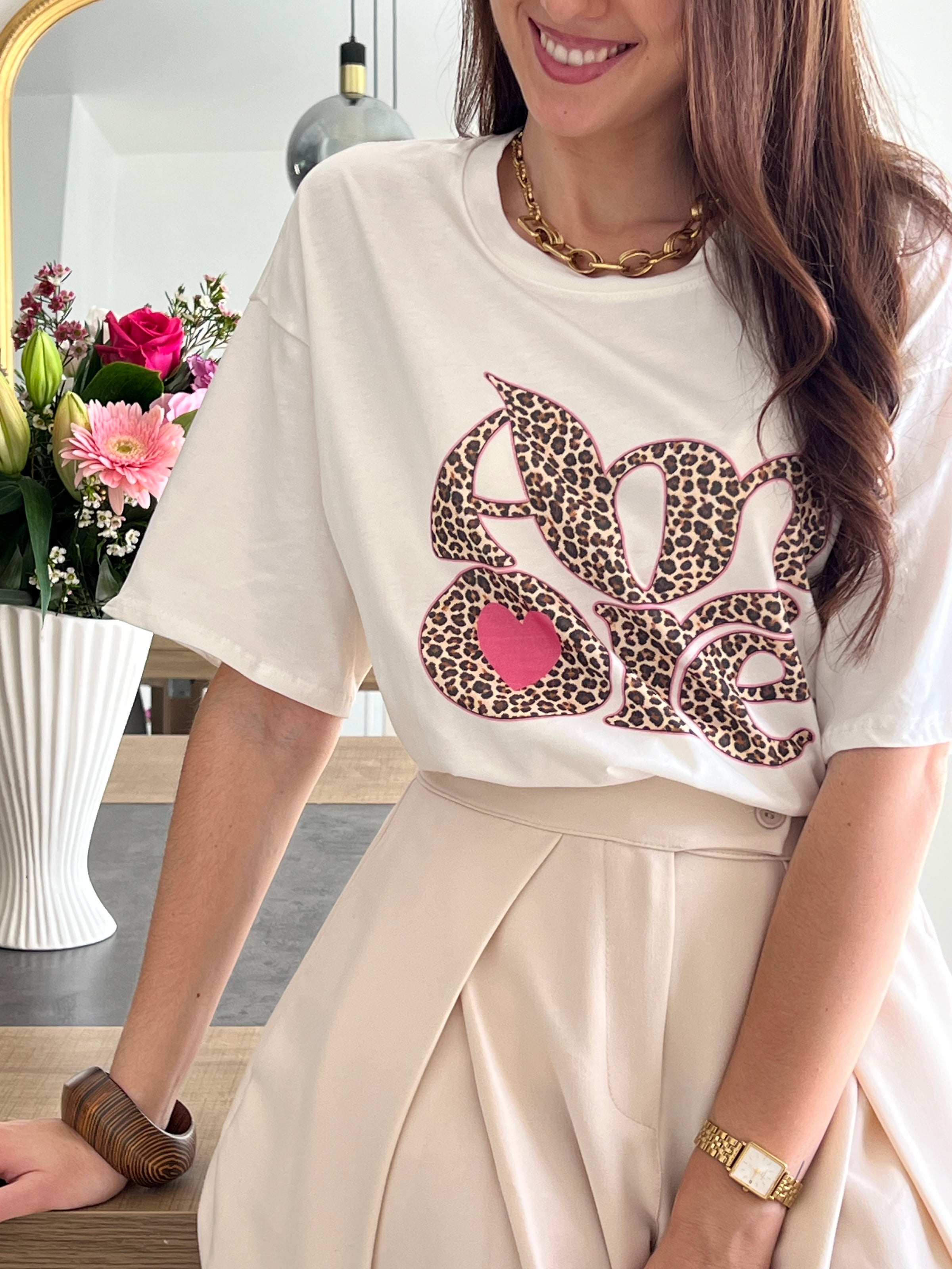 Tee-shirt blanc femme avec inscription "Amore" en motif léopard, parfait pour un look tendance et féminin. Conçu en 100% coton, il offre un confort optimal au quotidien grâce à ses manches courtes et son col rond. Ses touches de couleurs rose, beige, noir et marron apportent une note originale et facile à assortir. Un basique revisité, idéal pour un style chic et décontracté.