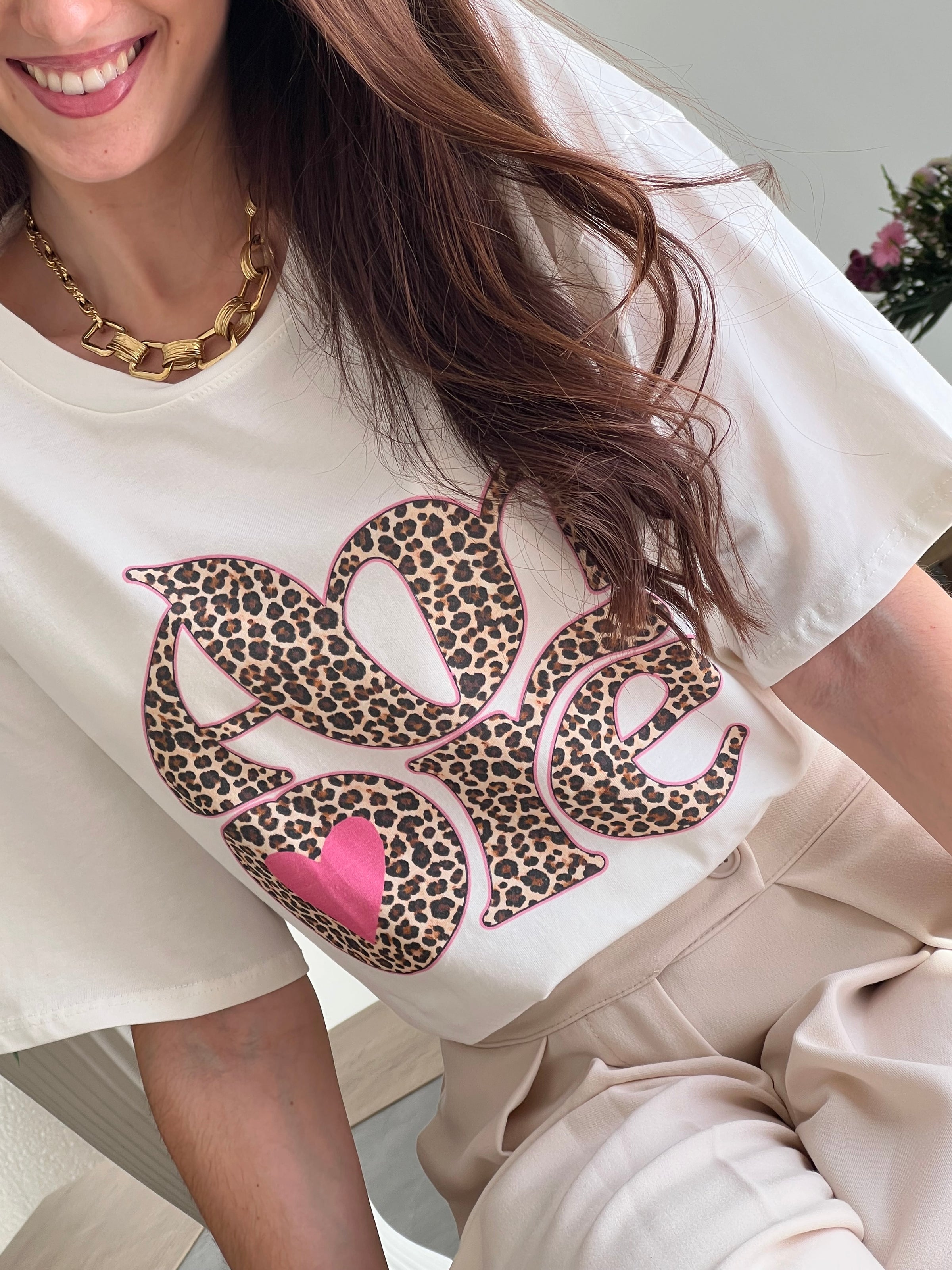 Tee-shirt blanc femme avec inscription "Amore" en motif léopard, parfait pour un look tendance et féminin. Conçu en 100% coton, il offre un confort optimal au quotidien grâce à ses manches courtes et son col rond. Ses touches de couleurs rose, beige, noir et marron apportent une note originale et facile à assortir. Un basique revisité, idéal pour un style chic et décontracté.