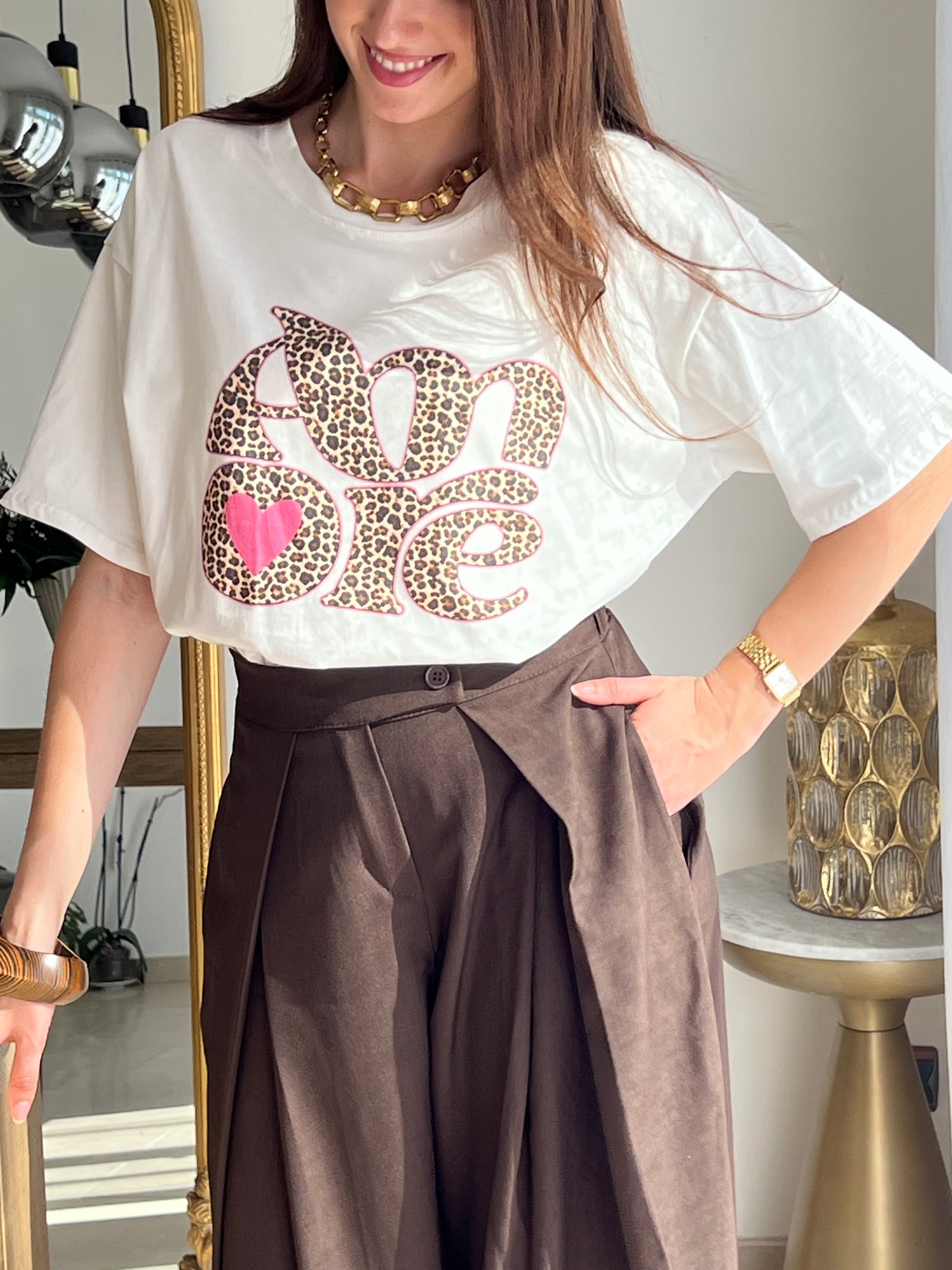 Tee-shirt blanc femme avec inscription "Amore" en motif léopard, parfait pour un look tendance et féminin. Conçu en 100% coton, il offre un confort optimal au quotidien grâce à ses manches courtes et son col rond. Ses touches de couleurs rose, beige, noir et marron apportent une note originale et facile à assortir. Un basique revisité, idéal pour un style chic et décontracté.