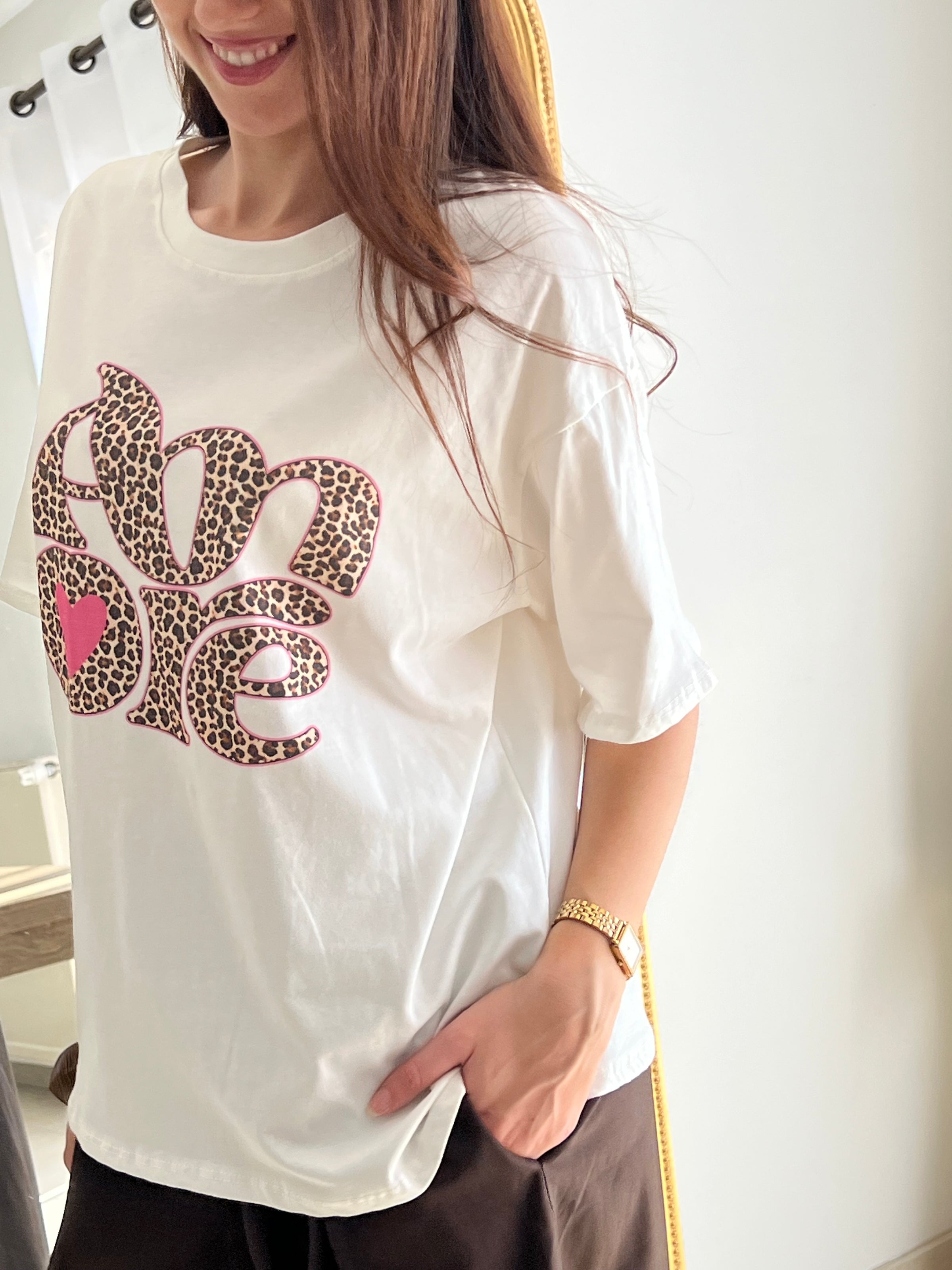Tee-shirt blanc femme avec inscription "Amore" en motif léopard, parfait pour un look tendance et féminin. Conçu en 100% coton, il offre un confort optimal au quotidien grâce à ses manches courtes et son col rond. Ses touches de couleurs rose, beige, noir et marron apportent une note originale et facile à assortir. Un basique revisité, idéal pour un style chic et décontracté.