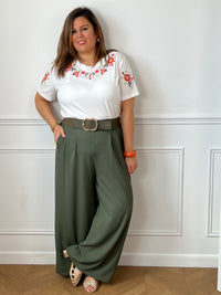 Tee-shirt blanc à fleurs brodées porté avec un pantalon kaki pour une tenue décontractée.
