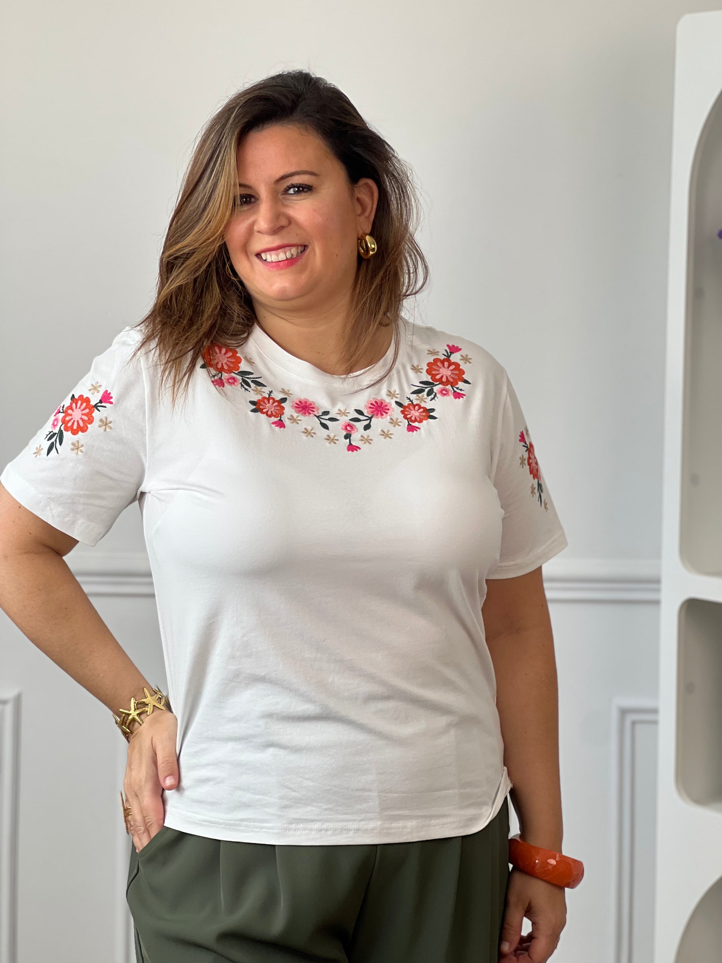 Tee-shirt blanc en coton avec manches courtes, col rond et broderies florales colorées.