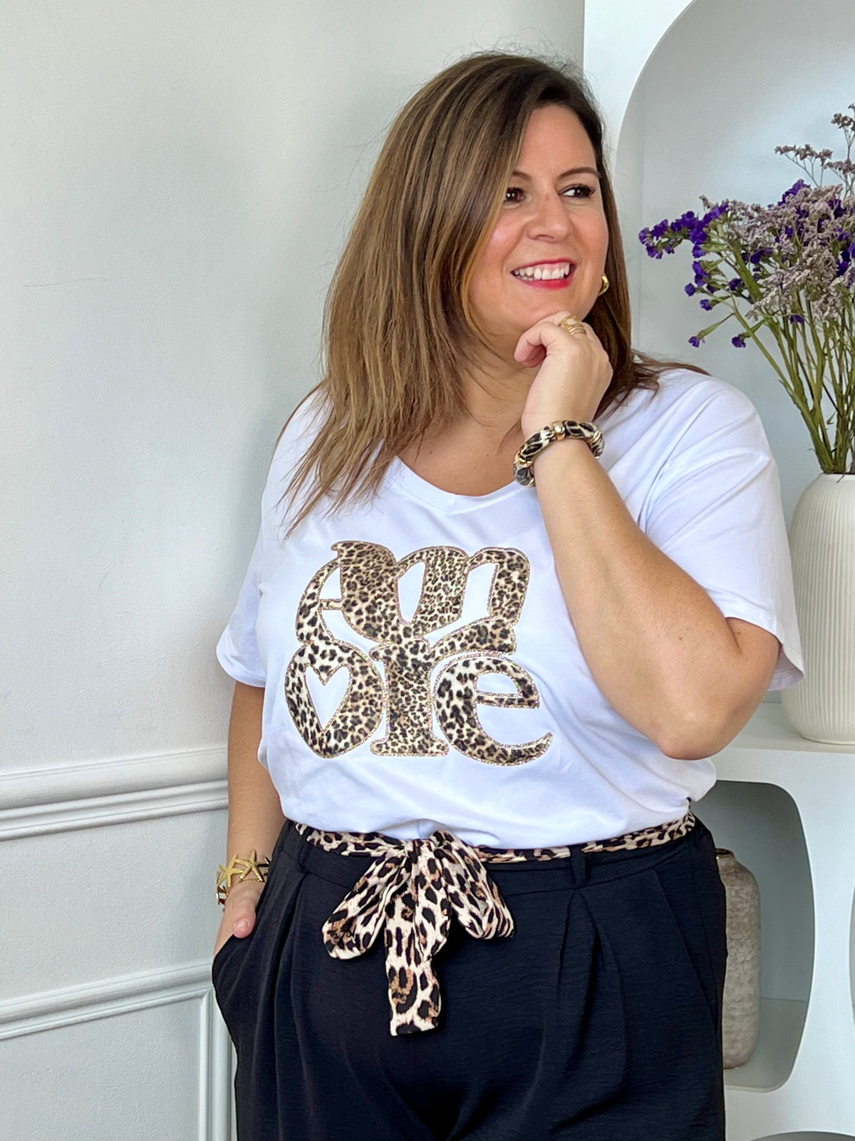 Apportez une touche tendance à votre dressing avec ce top grande taille femme au style moderne et féminin. Doté de manches courtes et d’un col V flatteur, il se distingue par son imprimé « Amore » en relief à motif léopard, sublimé par de délicats détails dorés. Ses nuances d’écru, marron, noir, doré et beige s’associent facilement à vos tenues du quotidien pour un look à la fois chic et décontracté.