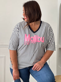 Apportez une touche de fraîcheur à vos tenues avec ce tee-shirt femme aux accents colorés et estivaux. Confectionné en 100% coton, il offre un confort optimal grâce à sa matière douce et légère. Son col V et ses manches courtes assurent une coupe féminine et agréable à porter, tandis que l’inscription rose « Malibu » apporte une note tendance et décontractée. Les rayures verticales bleu marine et écrues allongent visuellement la silhouette et complètent harmonieusement ce modèle aux teintes bleu marine et r