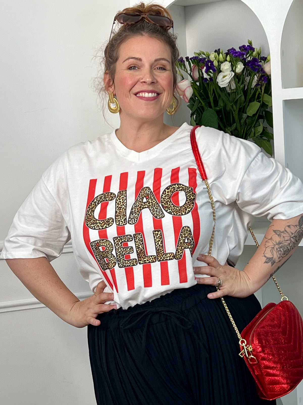 Tee-shirt blanc femme en 100% coton, parfait pour un look tendance et décontracté. Avec ses manches courtes, son col V et son inscription léopard "Ciao Bella", il apporte une touche moderne et originale. Ses rayures rouges verticales ajoutent du style et du caractère à la tenue. Confortable et facile à associer, ce tee-shirt aux tons blanc, rose, beige, noir et marron est idéal pour un look casual chic au quotidien.
