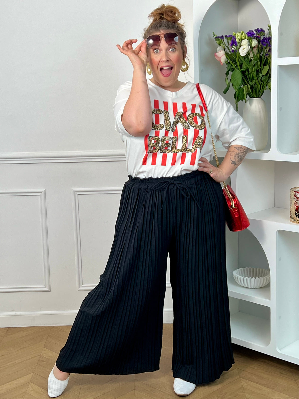 Tee-shirt blanc femme en 100% coton, parfait pour un look tendance et décontracté. Avec ses manches courtes, son col V et son inscription léopard "Ciao Bella", il apporte une touche moderne et originale. Ses rayures rouges verticales ajoutent du style et du caractère à la tenue. Confortable et facile à associer, ce tee-shirt aux tons blanc, rose, beige, noir et marron est idéal pour un look casual chic au quotidien.