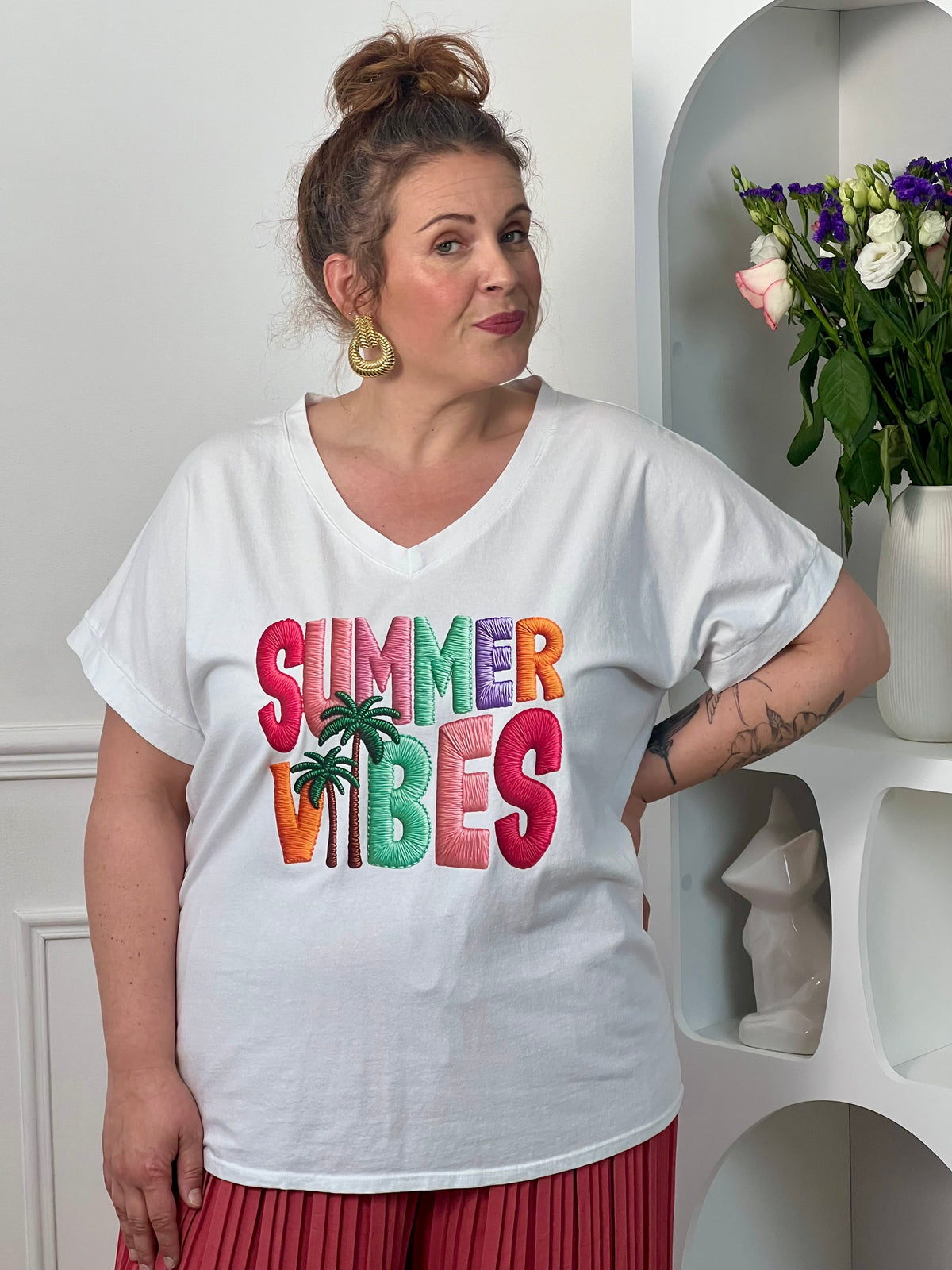 Tee-shirt blanc femme à manches courtes, parfait pour un look estival et décontracté. Avec son col V et son imprimé coloré "Summer Vibes" accompagné d’un motif palmier, il apporte une touche tendance et ensoleillée à vos tenues. Facile à associer, ce tee-shirt aux nuances rose, vert, violet et orange est idéal pour un style casual chic au quotidien.