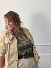 Tee-shirt kaki Livana à motifs cachemire écrus et noirs, porté sous une veste beige avec un pantalon écru.
