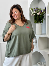 Tee-shirt kaki basique femme grande taille, parfait pour un look décontracté et tendance. Avec ses manches courtes, son col V et son cœur rouge floqué, il apporte une touche féminine et moderne. Confectionné en coton avec une pointe d’élasthanne, il offre confort, douceur et liberté de mouvement. Facile à associer, ce tee-shirt kaki est un indispensable du dressing grande taille.