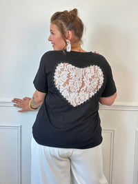 Ajoutez une touche de romantisme à vos tenues avec ce tee-shirt noir grande taille à la fois confortable et féminin. Doté d’un col rond et de manches courtes, il se distingue par son élégant empiècement en dentelle ajourée au dos, formant un délicat motif cœur. Confectionné dans une matière douce et légèrement extensible composée de 97% coton et 3% élasthanne, ce modèle noir et écru est idéal pour allier confort et style au quotidien.