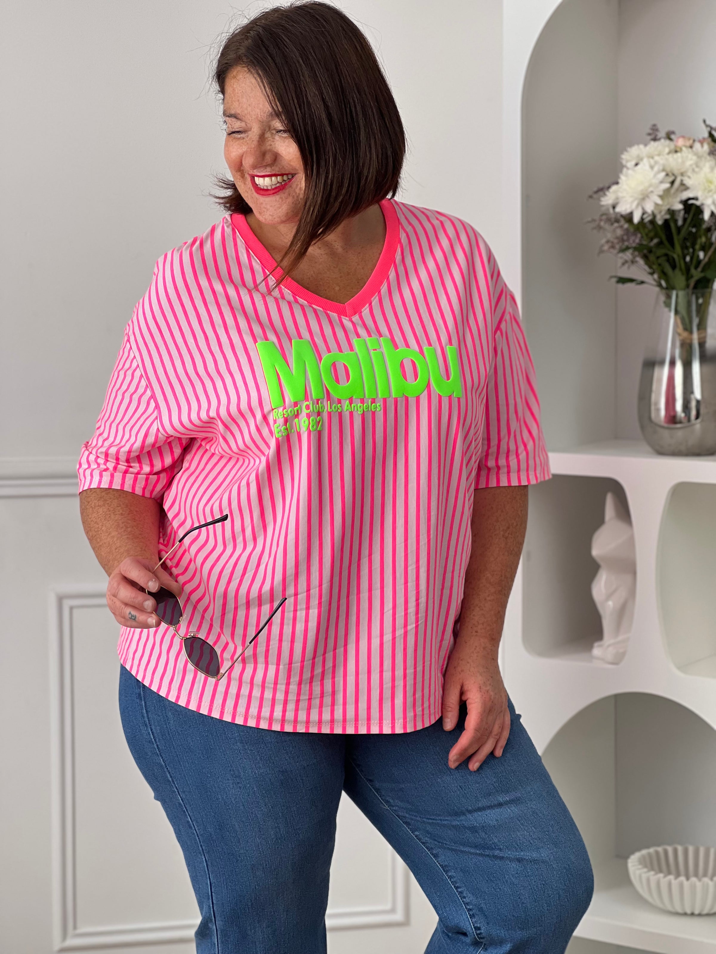 Ajoutez une touche de peps à votre dressing avec ce tee-shirt rose fluo au style résolument tendance. Confectionné en 100% coton, il offre un confort optimal au quotidien grâce à sa matière douce et légère. L’inscription vert fluo « Malibu » apporte une note estivale et dynamique. Les rayures verticales rose fluo et rose clair complètent son look moderne et coloré, idéal pour illuminer vos tenues décontractées.