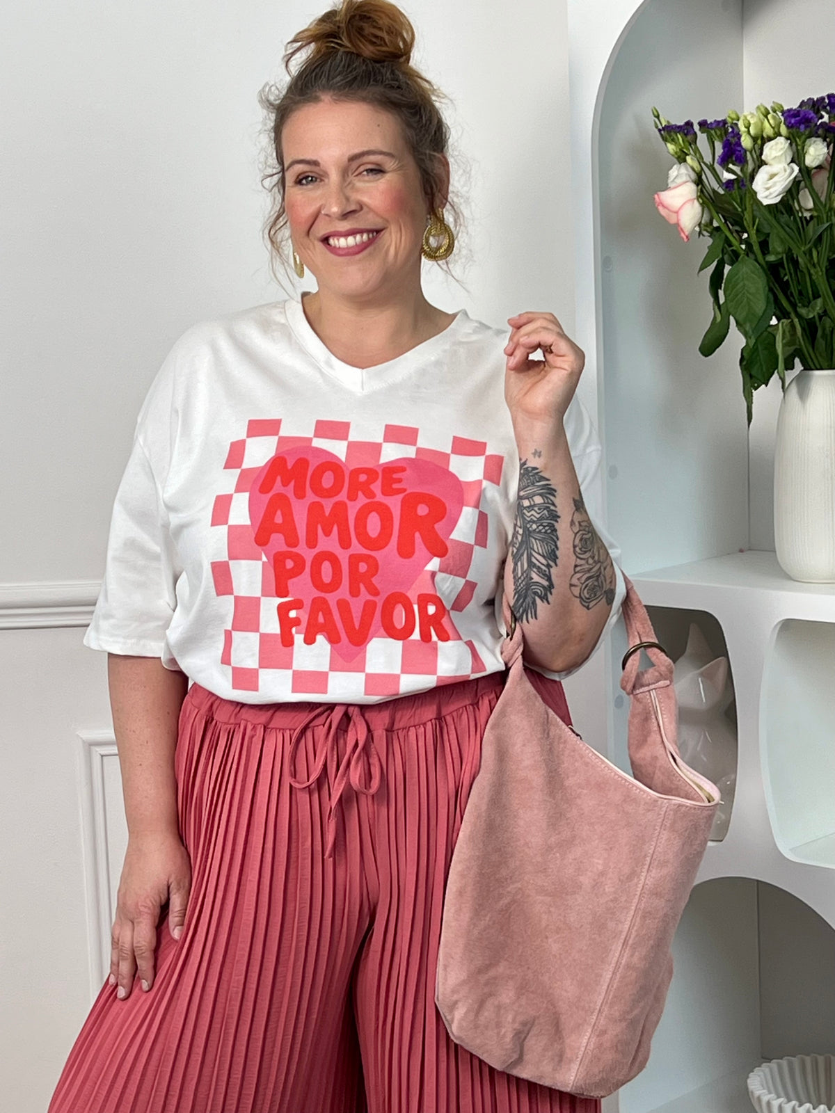 Tee-shirt blanc femme à manches courtes, idéal pour un look tendance et féminin. Doté d’un col V et d’une inscription rose "More Amor Por Favor", il apporte une touche moderne et romantique. Ses motifs cœur et quadrillage ajoutent du style et de l’originalité. Facile à porter au quotidien, ce tee-shirt aux couleurs blanc, rose et rouge est parfait pour une tenue casual chic.