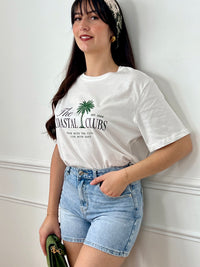 Tee-shirt écru femme à manches courtes, parfait pour un look décontracté et tendance. Avec son col rond et son imprimé "The Coastal Clubs" accompagné d’un motif palmier, il apporte une touche estivale et moderne. Facile à associer, ce tee-shirt aux tons écru, vert et noir est idéal pour compléter vos tenues casual du quotidien.