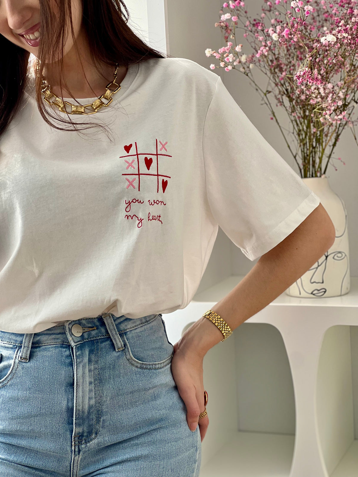 Craquez pour ce tee-shirt écru femme à manches courtes, à la fois doux et original. Doté d’un col rond et d’une inscription brodée “You won my heart” sur le devant et au dos, il est sublimé par des motifs de morpion avec cœurs et croix. Ses couleurs écru, rose et rouge apportent une touche romantique et tendance à votre tenue.