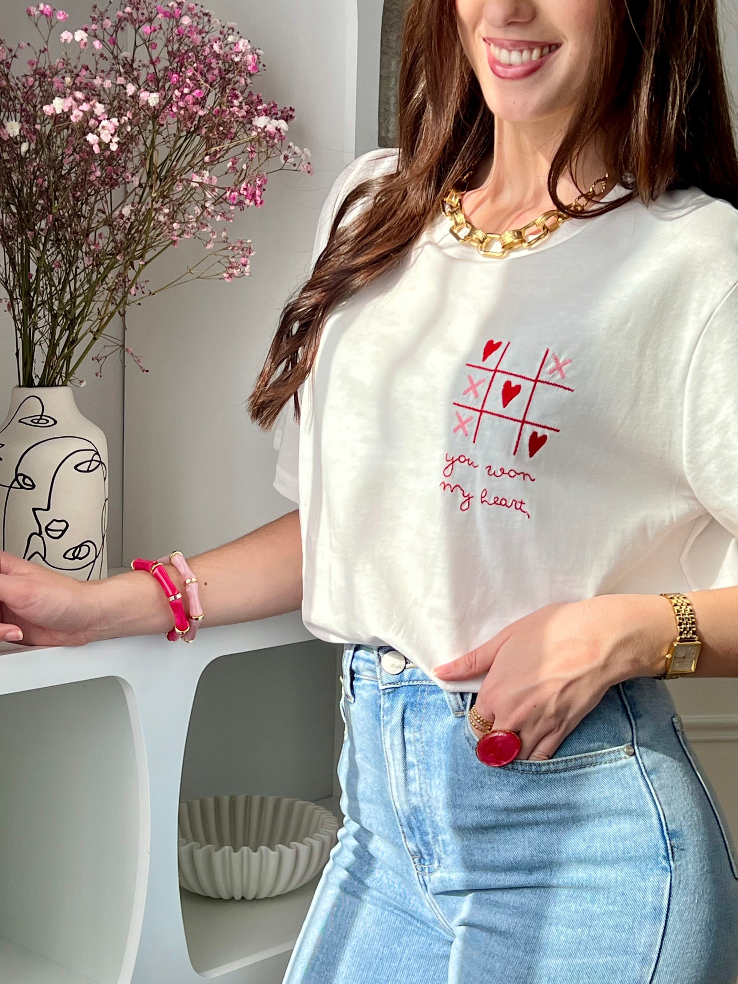 Craquez pour ce tee-shirt écru femme à manches courtes, à la fois doux et original. Doté d’un col rond et d’une inscription brodée “You won my heart” sur le devant et au dos, il est sublimé par des motifs de morpion avec cœurs et croix. Ses couleurs écru, rose et rouge apportent une touche romantique et tendance à votre tenue.