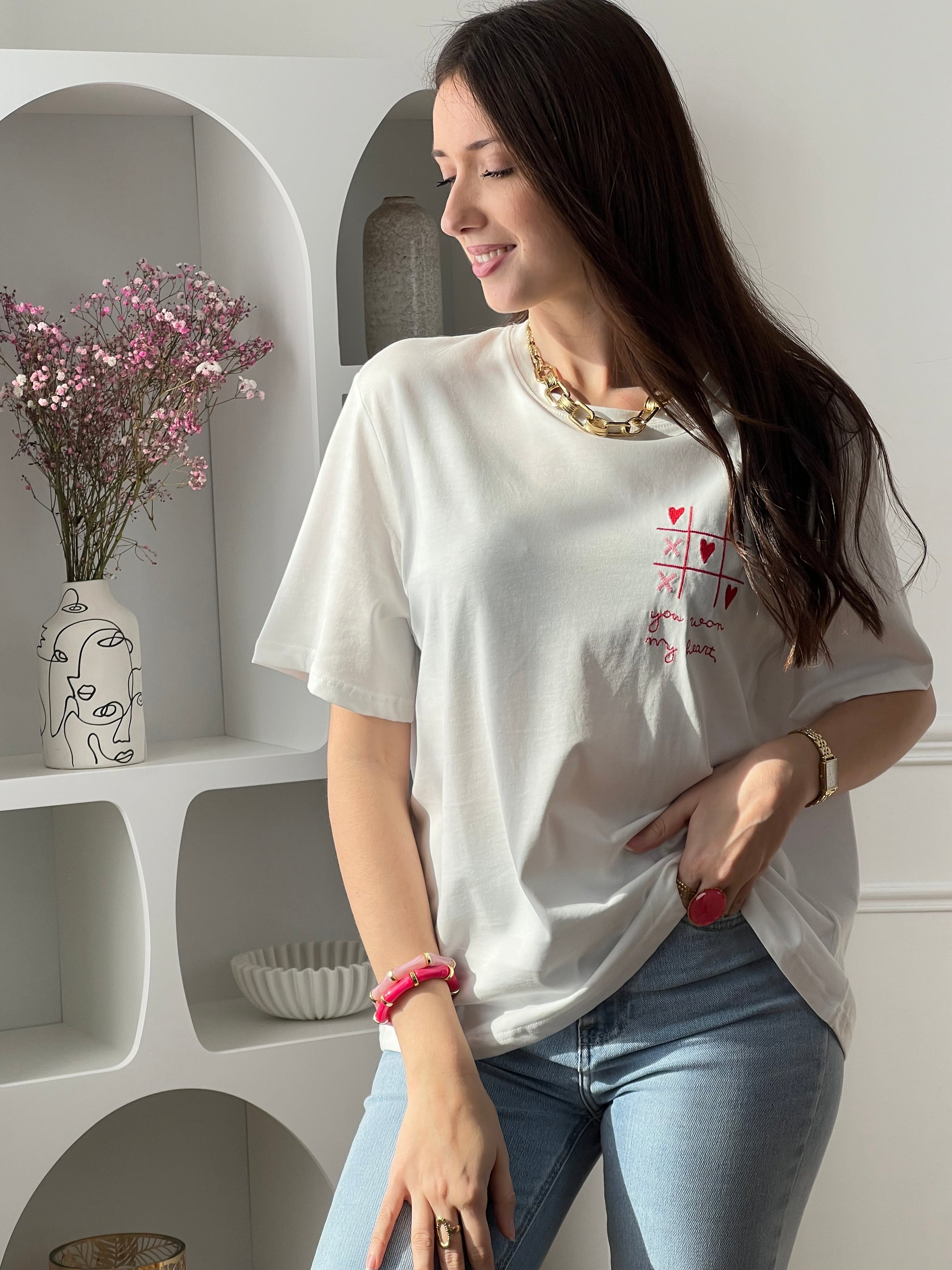 Craquez pour ce tee-shirt écru femme à manches courtes, à la fois doux et original. Doté d’un col rond et d’une inscription brodée “You won my heart” sur le devant et au dos, il est sublimé par des motifs de morpion avec cœurs et croix. Ses couleurs écru, rose et rouge apportent une touche romantique et tendance à votre tenue.
