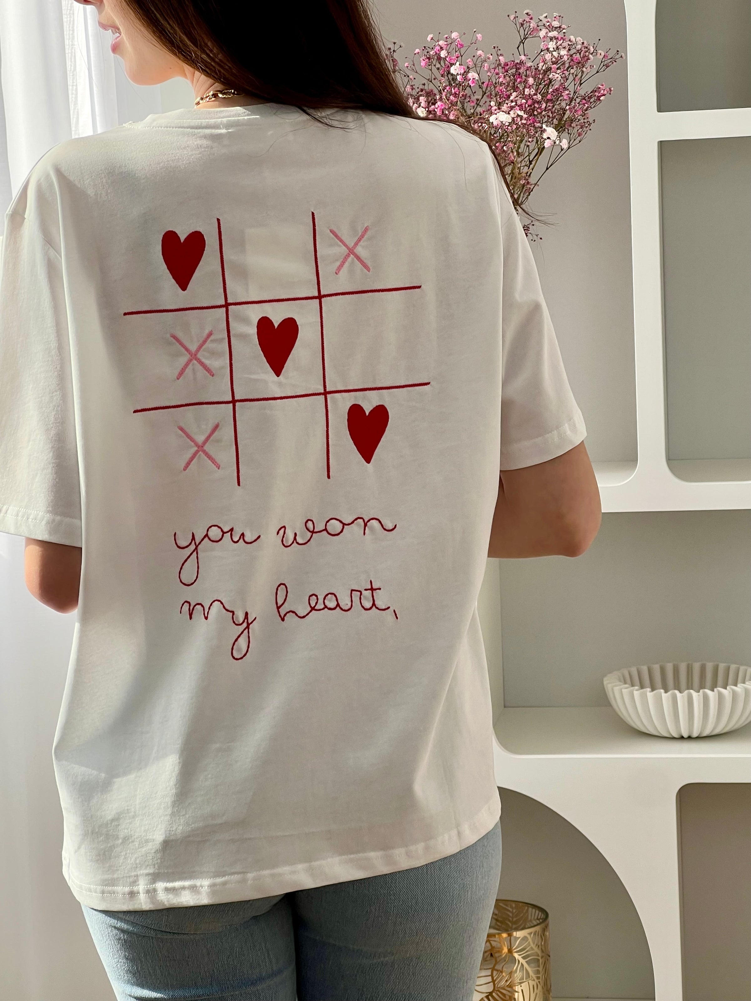 Craquez pour ce tee-shirt écru femme à manches courtes, à la fois doux et original. Doté d’un col rond et d’une inscription brodée “You won my heart” sur le devant et au dos, il est sublimé par des motifs de morpion avec cœurs et croix. Ses couleurs écru, rose et rouge apportent une touche romantique et tendance à votre tenue.
