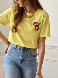 Top jaune femme à manches courtes, idéal pour un look tendance et confortable au quotidien. Doté d’un col rond et d’une inscription colorée "Now or Never Love Today" à l’avant et au dos, ce t-shirt apporte une touche moderne et positive à votre tenue. Confectionné en coton avec une pointe d’élasthanne, il offre douceur, élasticité et aisance.