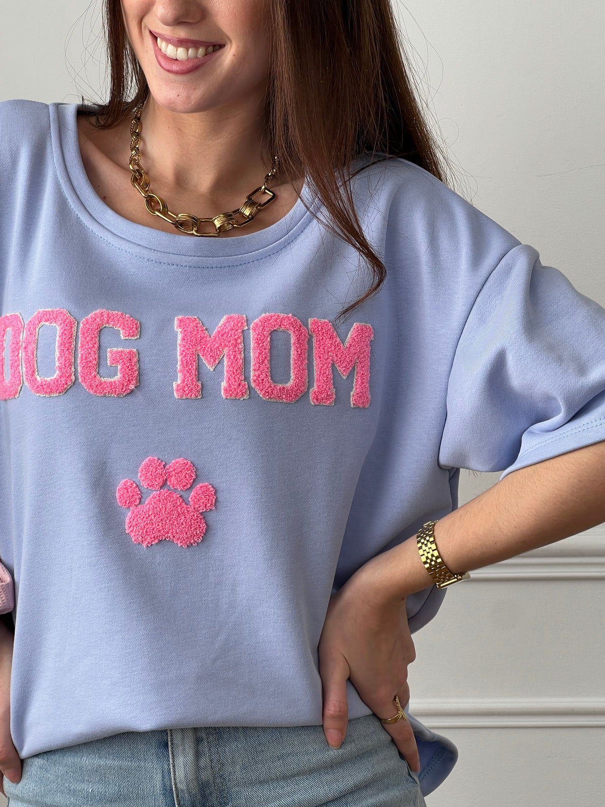 Craquez pour ce tee-shirt style sweat femme, confortable et tendance. Doté de manches courtes et d’un col rond, il est confectionné en 100 % coton pour un confort optimal. Son inscription “Dog mom” en rose et écru avec une patte de chien apporte une touche fun et originale. Ses couleurs bleu, rose et écru en font une pièce facile à porter au quotidien.