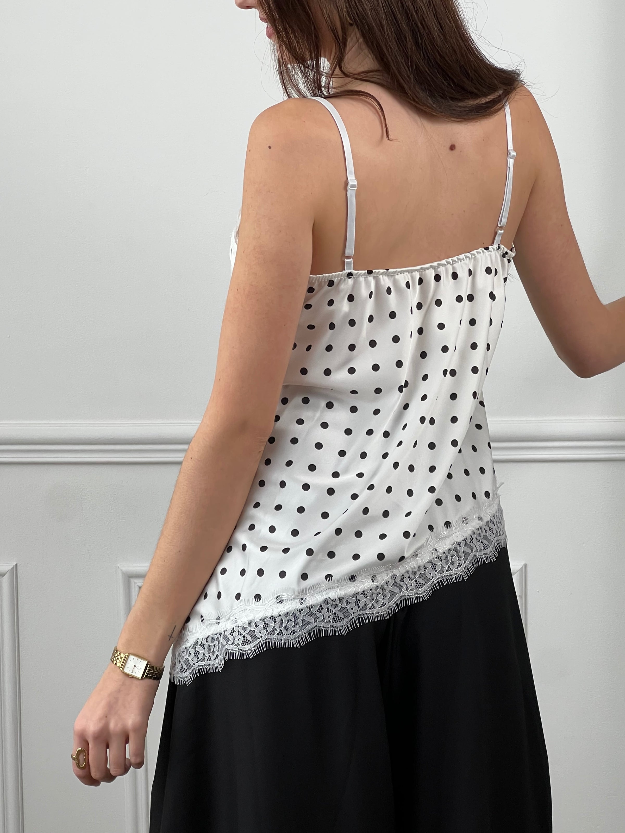 Top écru à pois noirs pour femme, élégant et tendance, parfait pour un look chic au quotidien.&nbsp;Ce top à bretelles réglables offre un confort optimal avec son col V délicatement orné de dentelle.&nbsp;Sa coupe asymétrique et ses finitions en dentelle sur le devant apportent une touche féminine et moderne.