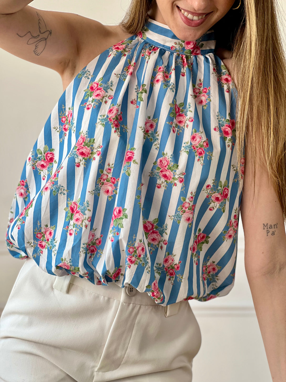 Top court à rayures femme, léger et féminin, parfait pour un look estival tendance. Doté de manches courtes à volants et d’un col montant avec liens à nouer au dos, il apporte une touche élégante et raffinée. Doublé et élastiqué sur le bas avec un effet bouffant, il offre confort et style au quotidien. Ses rayures verticales bleues et écrues, associées à ses motifs fleurs roses, ajoutent une note fraîche et colorée. Confectionné en viscose et coton, ce top aux tons écru, bleu, vert et rose est idéal pour un