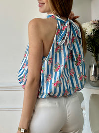 Top court à rayures femme, léger et féminin, parfait pour un look estival tendance. Doté de manches courtes à volants et d’un col montant avec liens à nouer au dos, il apporte une touche élégante et raffinée. Doublé et élastiqué sur le bas avec un effet bouffant, il offre confort et style au quotidien. Ses rayures verticales bleues et écrues, associées à ses motifs fleurs roses, ajoutent une note fraîche et colorée. Confectionné en viscose et coton, ce top aux tons écru, bleu, vert et rose est idéal pour un