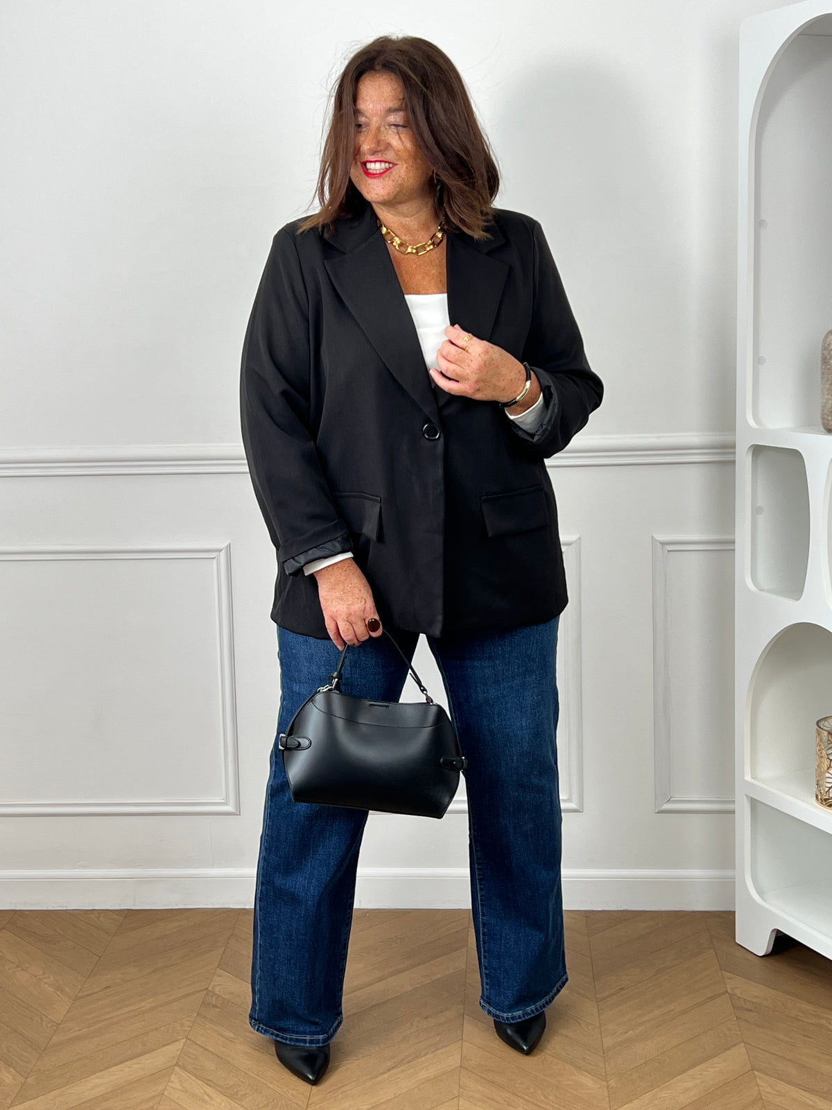 Top blanc col carré grande taille porté avec un blazer noir oversize, jean wide leg bleu et sac bowling noir - look chic et élégant