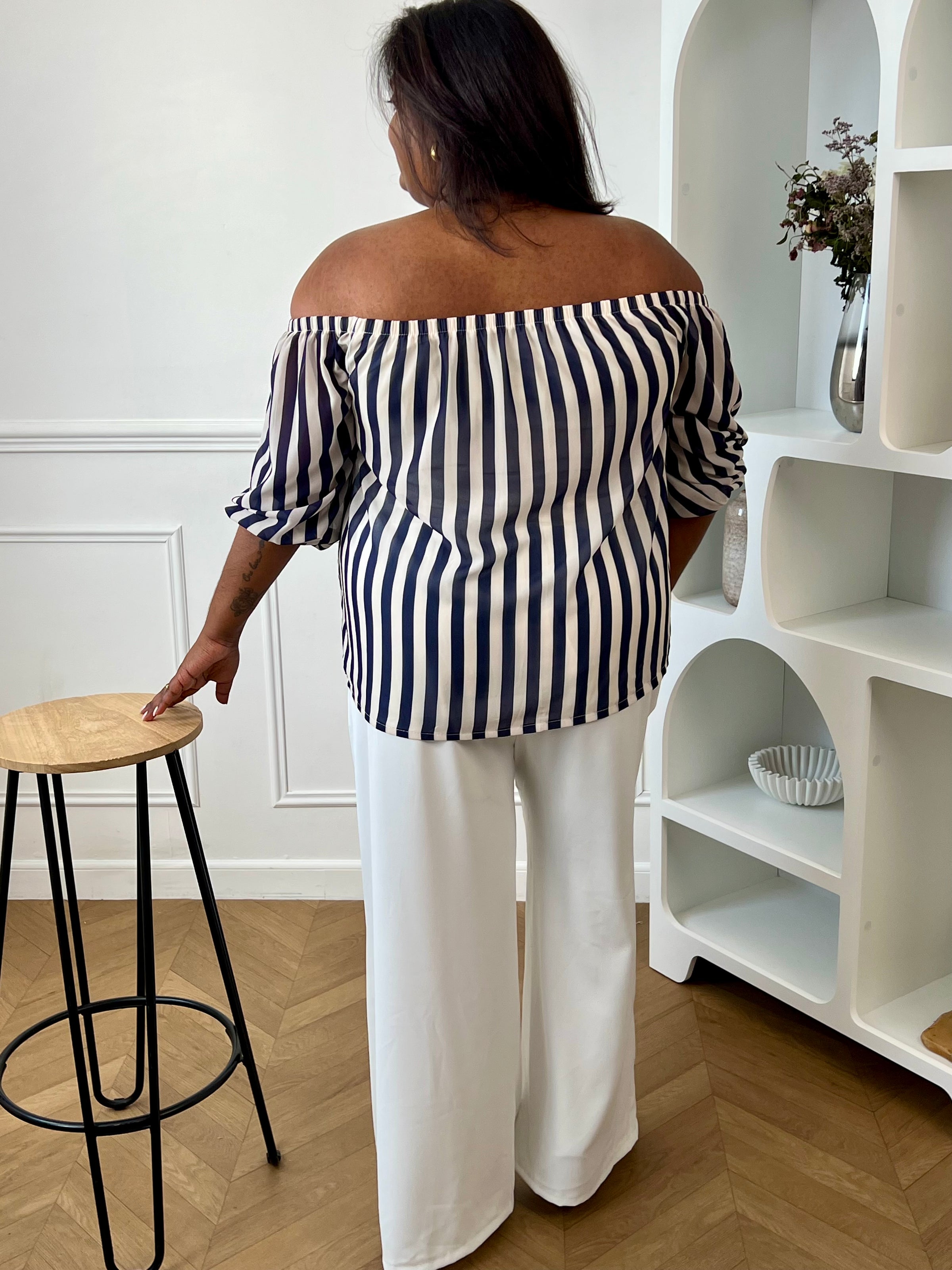 Apportez une touche d’élégance à votre dressing avec cette blouse grande taille à col bateau. Légère et fluide, elle offre un tombé féminin et confortable, idéal pour le quotidien. Ses manches courtes amples et son col bateau élastique assurent une allure décontractée et raffinée, tandis que les rayures verticales bleu marine et écru allongent visuellement la silhouette. Doublée sur le corps pour plus de confort et légèrement transparente aux manches, cette blouse est parfaite pour un look chic et intempore