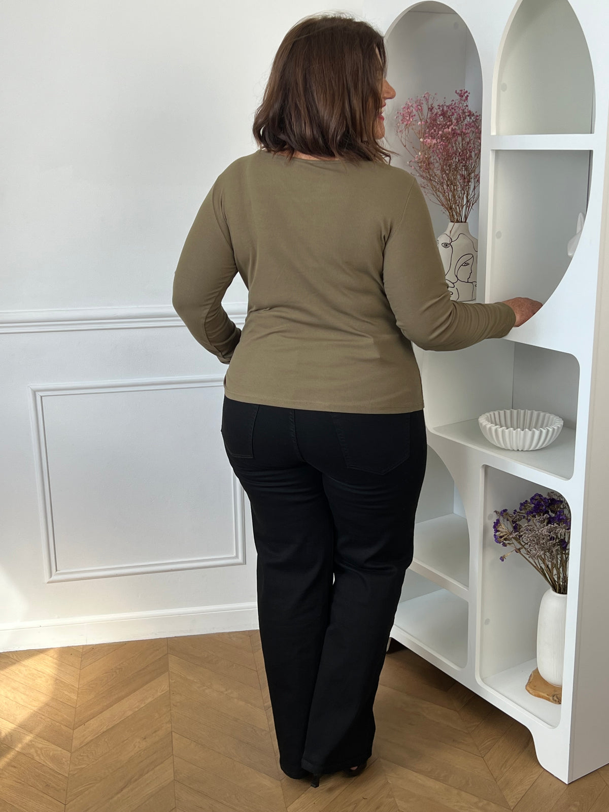 Top kaki Alix porté de dos avec un pantalon noir, montrant sa coupe près du corps et ses manches longues.