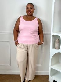 Top rose clair grande taille porté avec un pantalon beige pour un look coloré et tendance.
