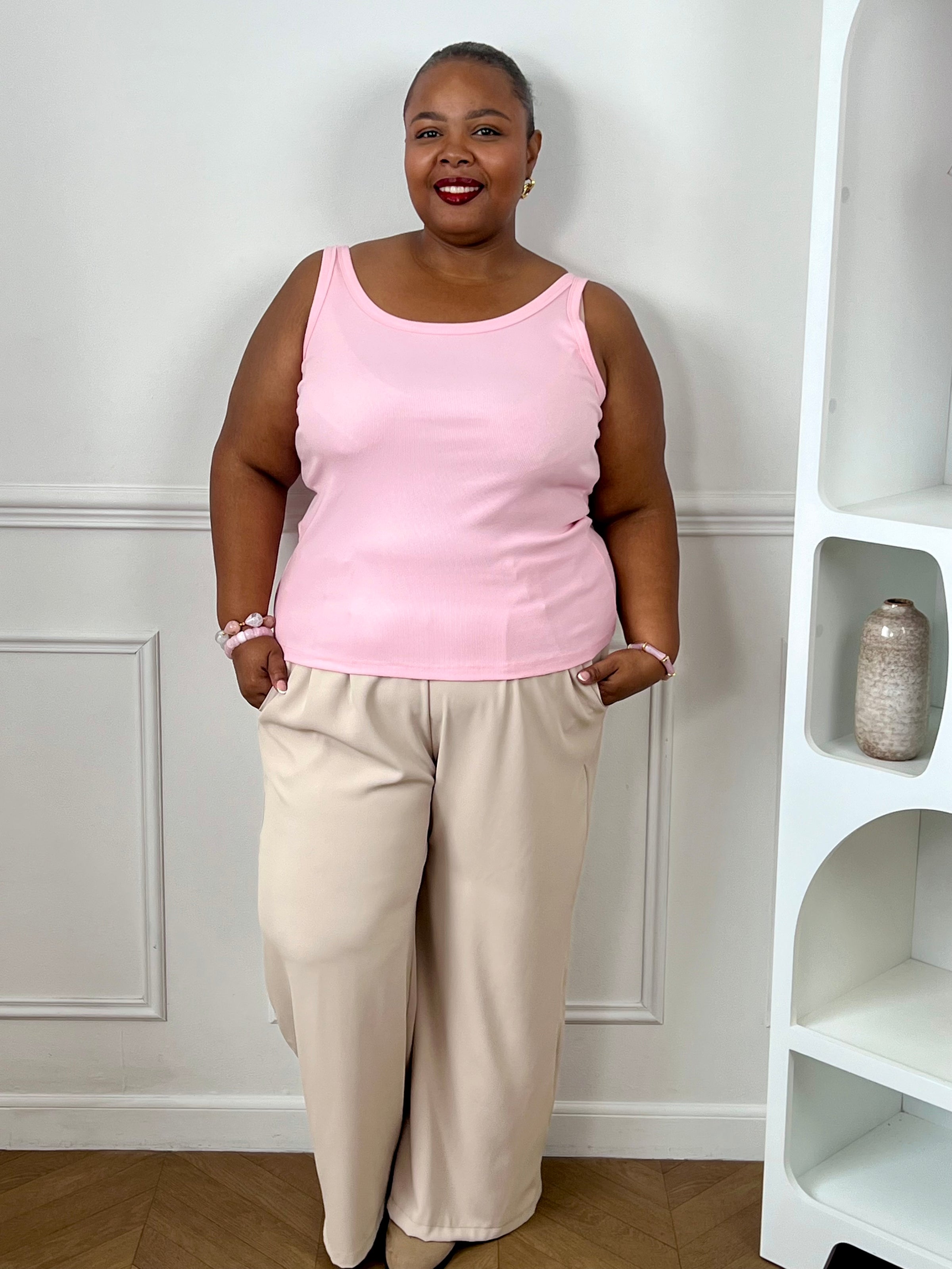 Top rose clair grande taille porté avec un pantalon beige pour un look coloré et tendance.