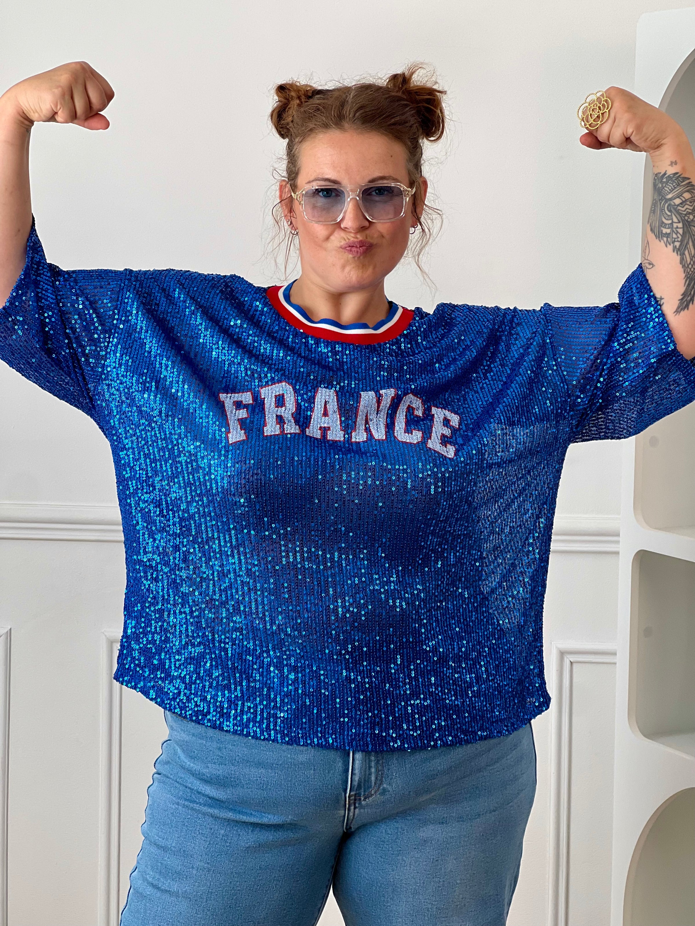 Affichez vos couleurs avec ce top bleu à sequins grande taille femme, parfait pour un look festif et original. Entièrement recouvert de sequins scintillants, il attire tous les regards tout en offrant une allure tendance. Son col rond en tissu et ses manches courtes garantissent un confort optimal, tandis que l’inscription « France » met à l’honneur les couleurs emblématiques bleu, blanc et rouge. Une pièce idéale pour soutenir votre équipe ou apporter une touche de brillance à vos tenues.