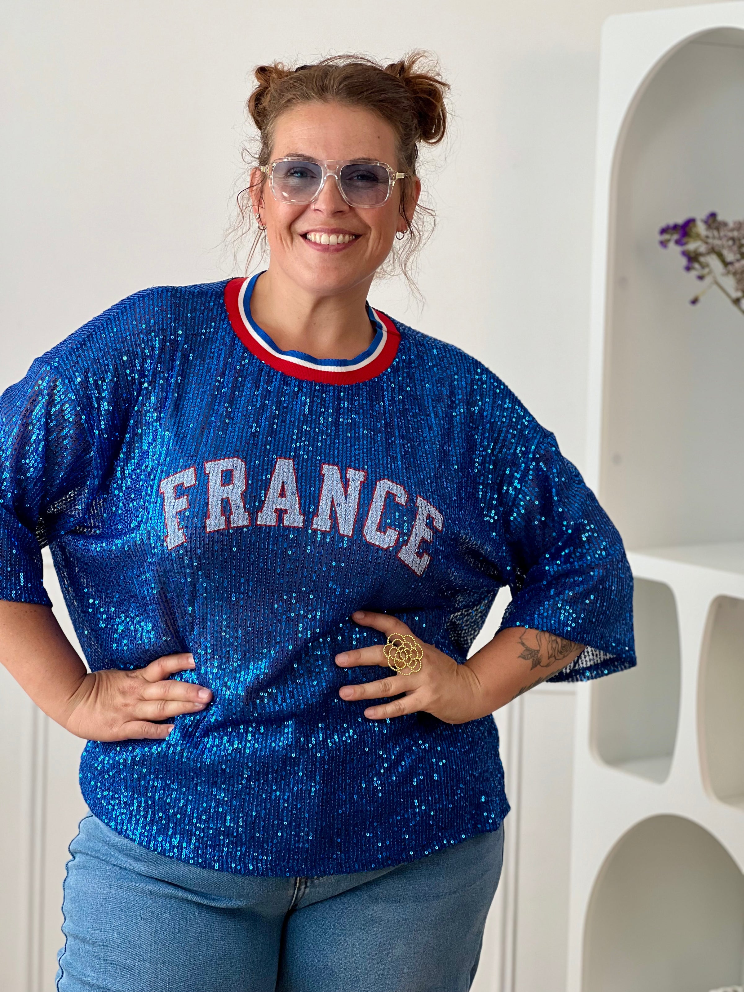 Affichez vos couleurs avec ce top bleu à sequins grande taille femme, parfait pour un look festif et original. Entièrement recouvert de sequins scintillants, il attire tous les regards tout en offrant une allure tendance. Son col rond en tissu et ses manches courtes garantissent un confort optimal, tandis que l’inscription « France » met à l’honneur les couleurs emblématiques bleu, blanc et rouge. Une pièce idéale pour soutenir votre équipe ou apporter une touche de brillance à vos tenues.