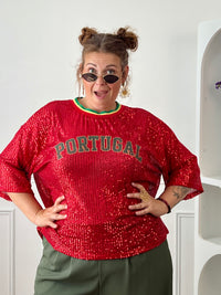 Affichez votre passion avec ce top rouge à sequins grande taille femme, parfait pour un look festif et tendance. Entièrement recouvert de sequins scintillants, il attire tous les regards tout en apportant une touche de glamour. Son col rond en tissu et ses manches courtes offrent un confort optimal, tandis que l’inscription « Portugal » met à l’honneur les couleurs emblématiques rouge, vert et jaune. Une pièce originale et lumineuse, idéale pour soutenir votre équipe ou dynamiser vos tenues.