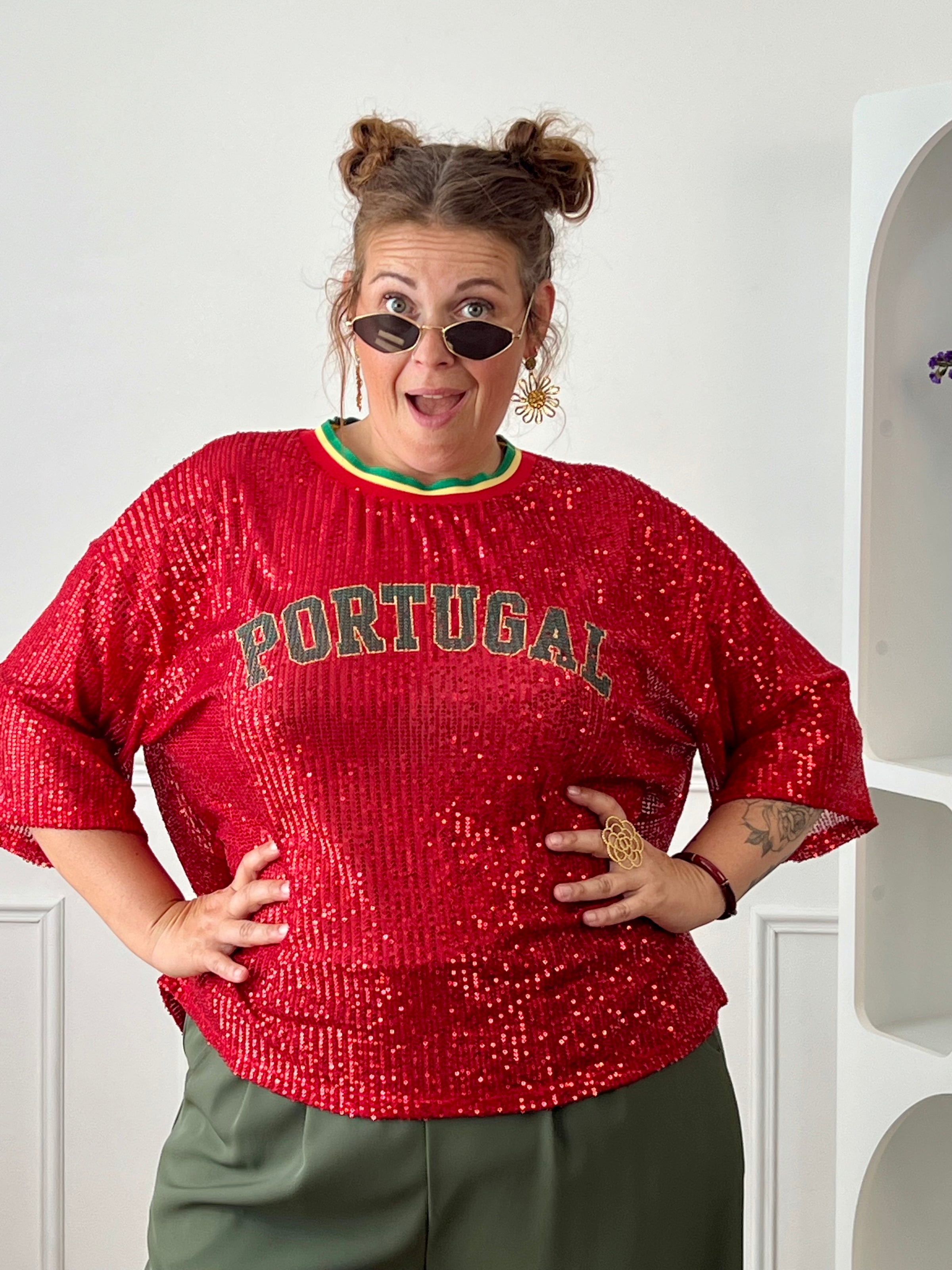 Affichez votre passion avec ce top rouge à sequins grande taille femme, parfait pour un look festif et tendance. Entièrement recouvert de sequins scintillants, il attire tous les regards tout en apportant une touche de glamour. Son col rond en tissu et ses manches courtes offrent un confort optimal, tandis que l’inscription « Portugal » met à l’honneur les couleurs emblématiques rouge, vert et jaune. Une pièce originale et lumineuse, idéale pour soutenir votre équipe ou dynamiser vos tenues.