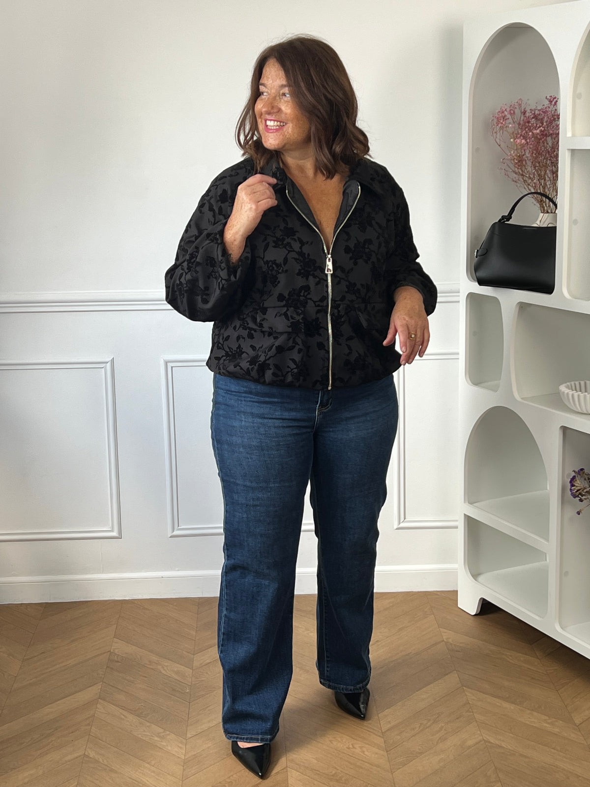 Veste noire Isée grande taille portée de face avec un jean bleu et des chaussures noires, montrant sa coupe ample.
