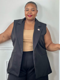 Veste noire cintrée grande taille femme sans manches, portée avec un top beige.