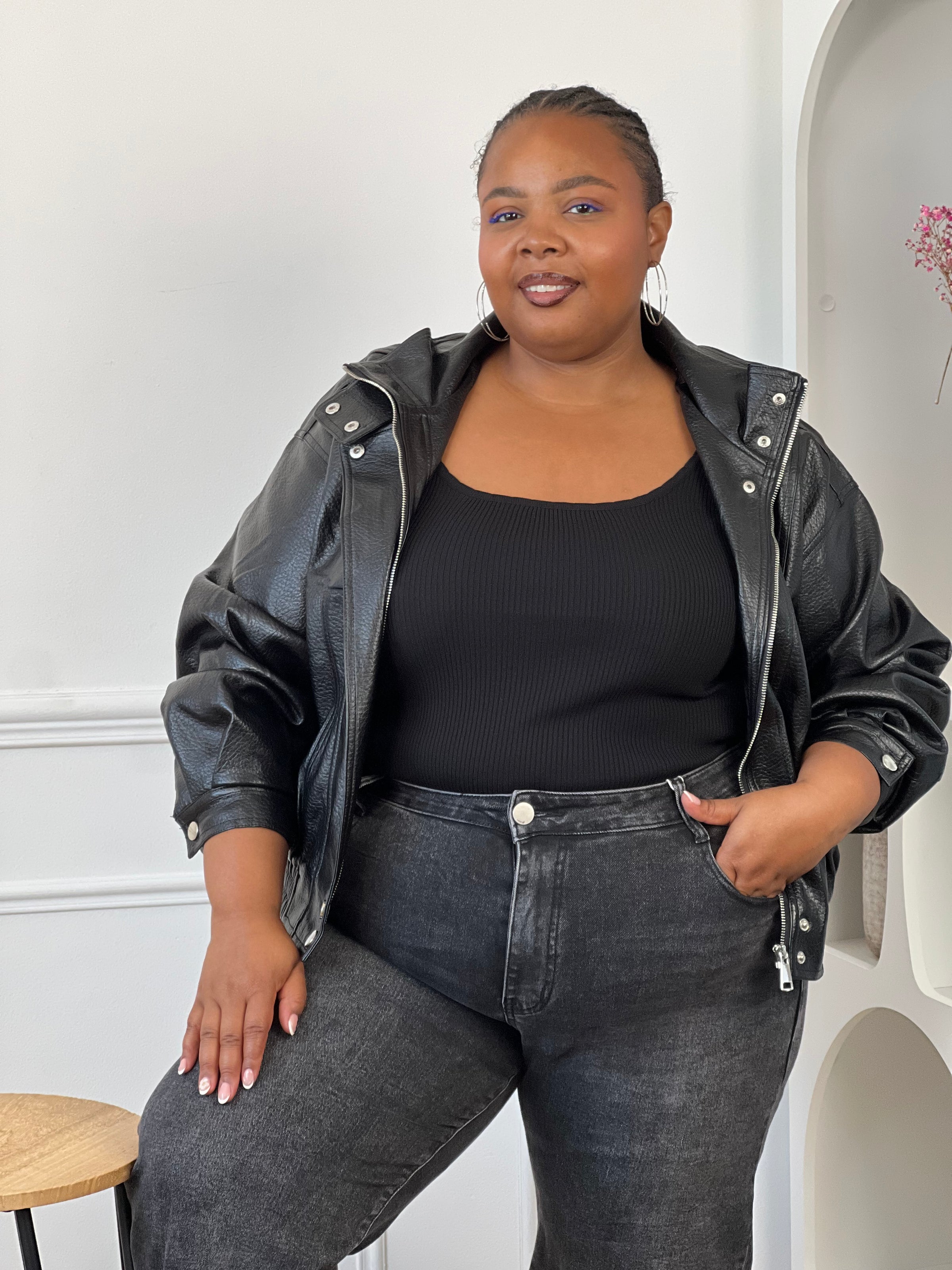 Veste noire style bomber avec boutons-pression et poches latérales.