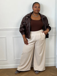 Veste bomber chocolat portée ouverte avec un pantalon large beige pour une tenue décontractée.