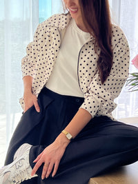 Veste femme écrue à pois noirs, légère et tendance, parfaite pour compléter un look chic et décontracté. Dotée de manches longues, d’une fermeture éclair et de poches latérales pratiques, elle allie style et fonctionnalité. Les boutons aux manches et l’élastique sur le bas apportent une finition moderne et confortable. Un indispensable facile à porter en toute saison.