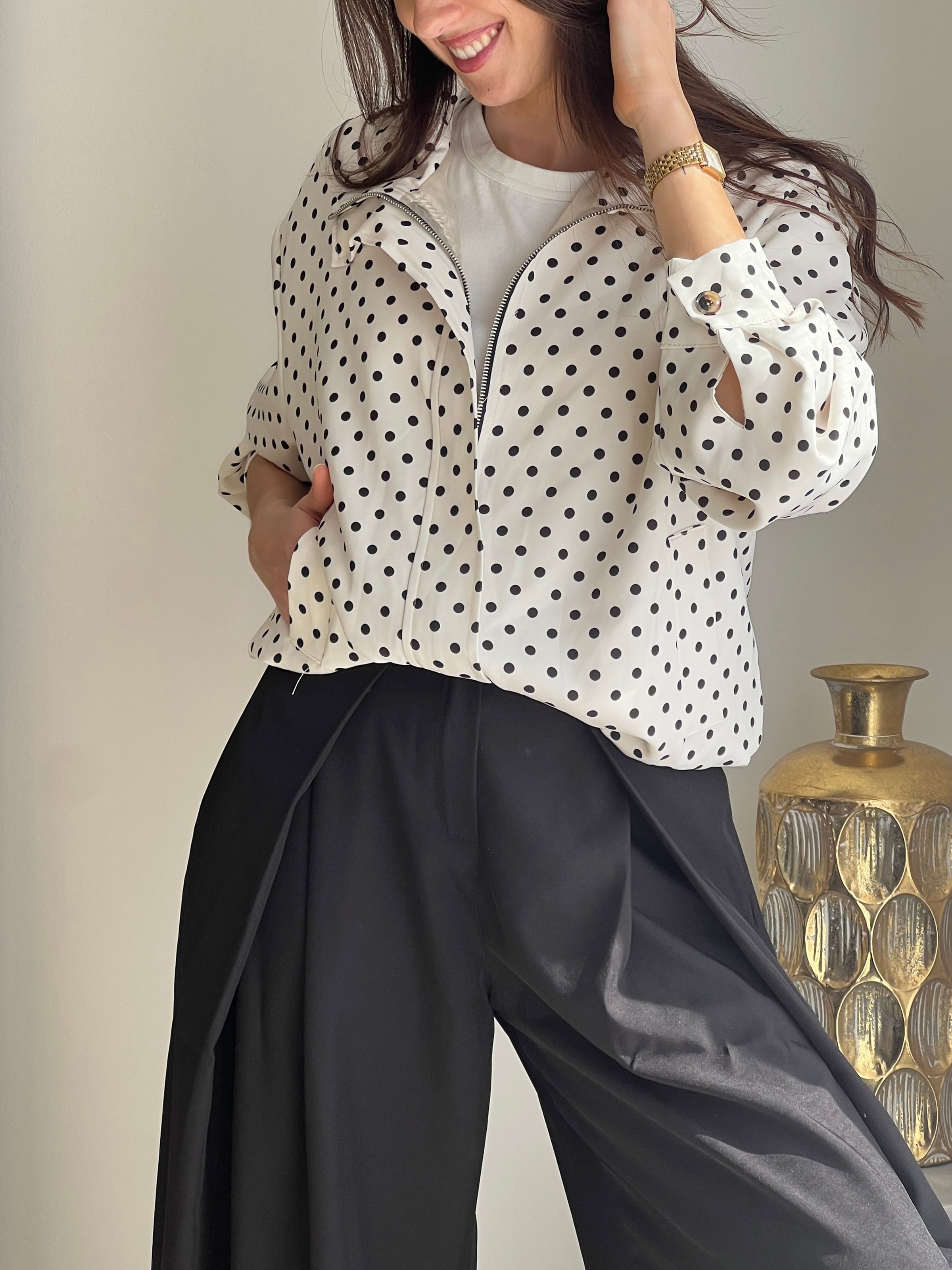 Veste femme écrue à pois noirs, légère et tendance, parfaite pour compléter un look chic et décontracté. Dotée de manches longues, d’une fermeture éclair et de poches latérales pratiques, elle allie style et fonctionnalité. Les boutons aux manches et l’élastique sur le bas apportent une finition moderne et confortable. Un indispensable facile à porter en toute saison.