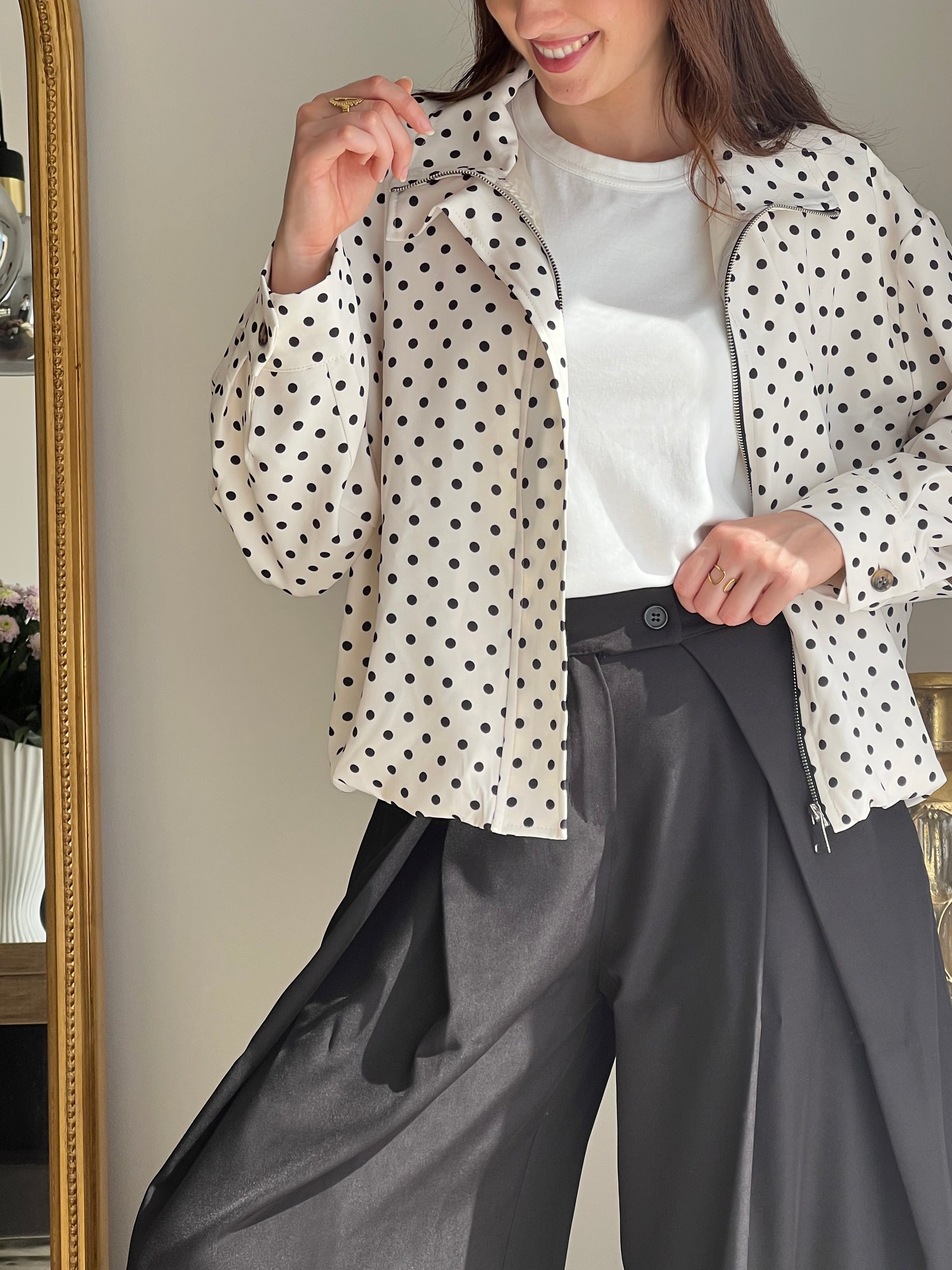 Veste femme écrue à pois noirs, légère et tendance, parfaite pour compléter un look chic et décontracté. Dotée de manches longues, d’une fermeture éclair et de poches latérales pratiques, elle allie style et fonctionnalité. Les boutons aux manches et l’élastique sur le bas apportent une finition moderne et confortable. Un indispensable facile à porter en toute saison.