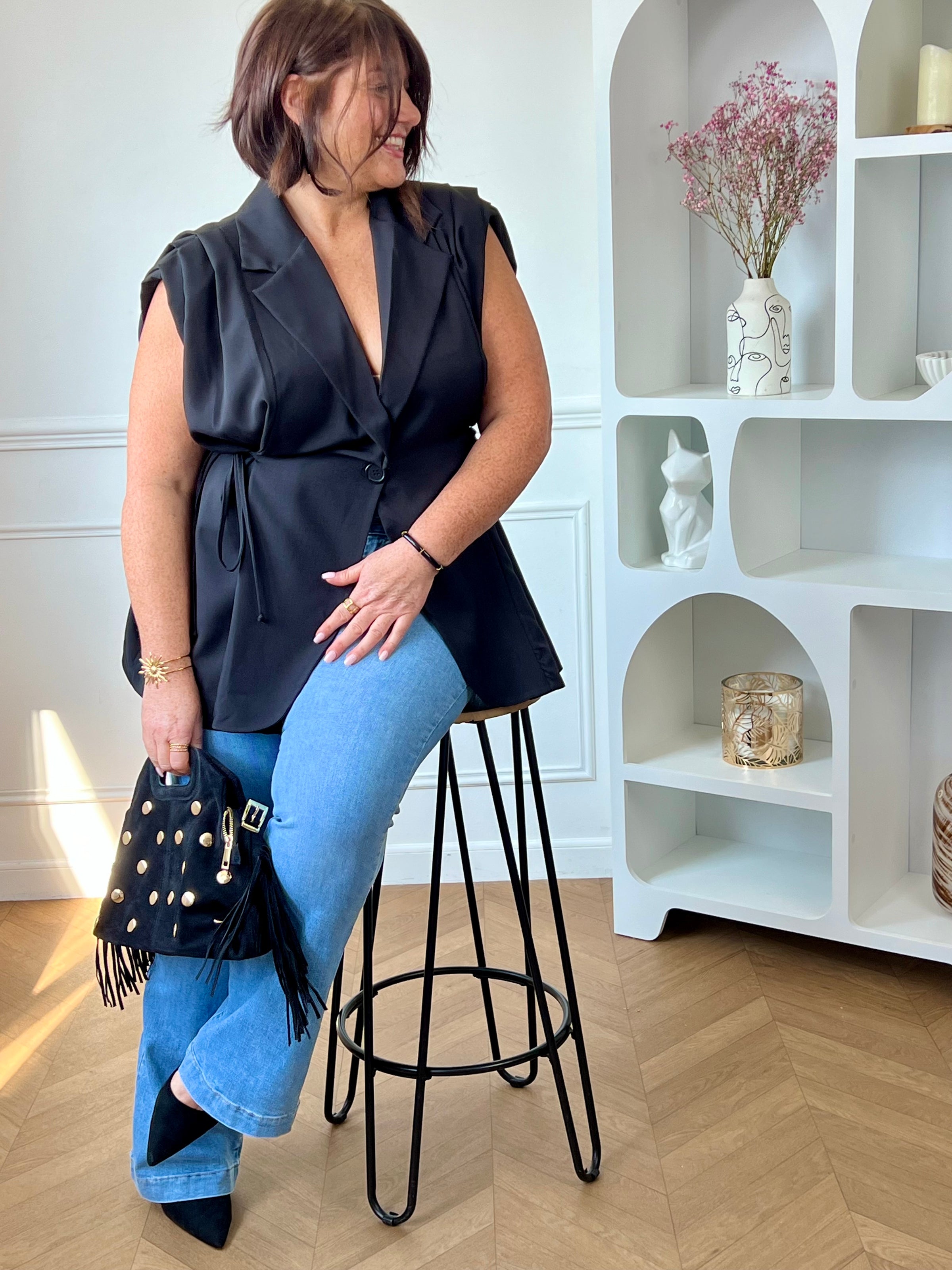 Veste noire cintrée grande taille femme, idéale pour structurer votre silhouette avec élégance. Sans manches, elle se distingue par ses épaules froncées et son col à revers pour une touche chic. Dotée de liens à nouer sur les côtés pour ajuster la taille et d’un bouton sur le devant, elle allie style et praticité. Entièrement doublée, cette veste noire est parfaite pour compléter vos tenues avec modernité.