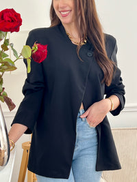 Optez pour cette veste noire femme au style moderne et structuré. Sa coupe asymétrique croisée sur le devant lui apporte une allure élégante et originale. Dotée de manches longues, d’un col montant et d’un bouton sur le haut, elle est doublée pour plus de confort. Une veste noire chic, idéale pour compléter vos tenues.