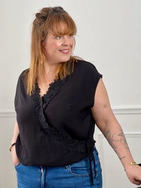Craquez pour ce top croisé noir grande taille femme, lumineux et féminin. Sans manches, il se distingue par sa fermeture croisée avec lien à nouer effet portefeuille qui sublime la silhouette. Son col V avec clip et ses motifs fleurs brodés apportent une touche délicate et élégante à ce modèle corail plein de charme.