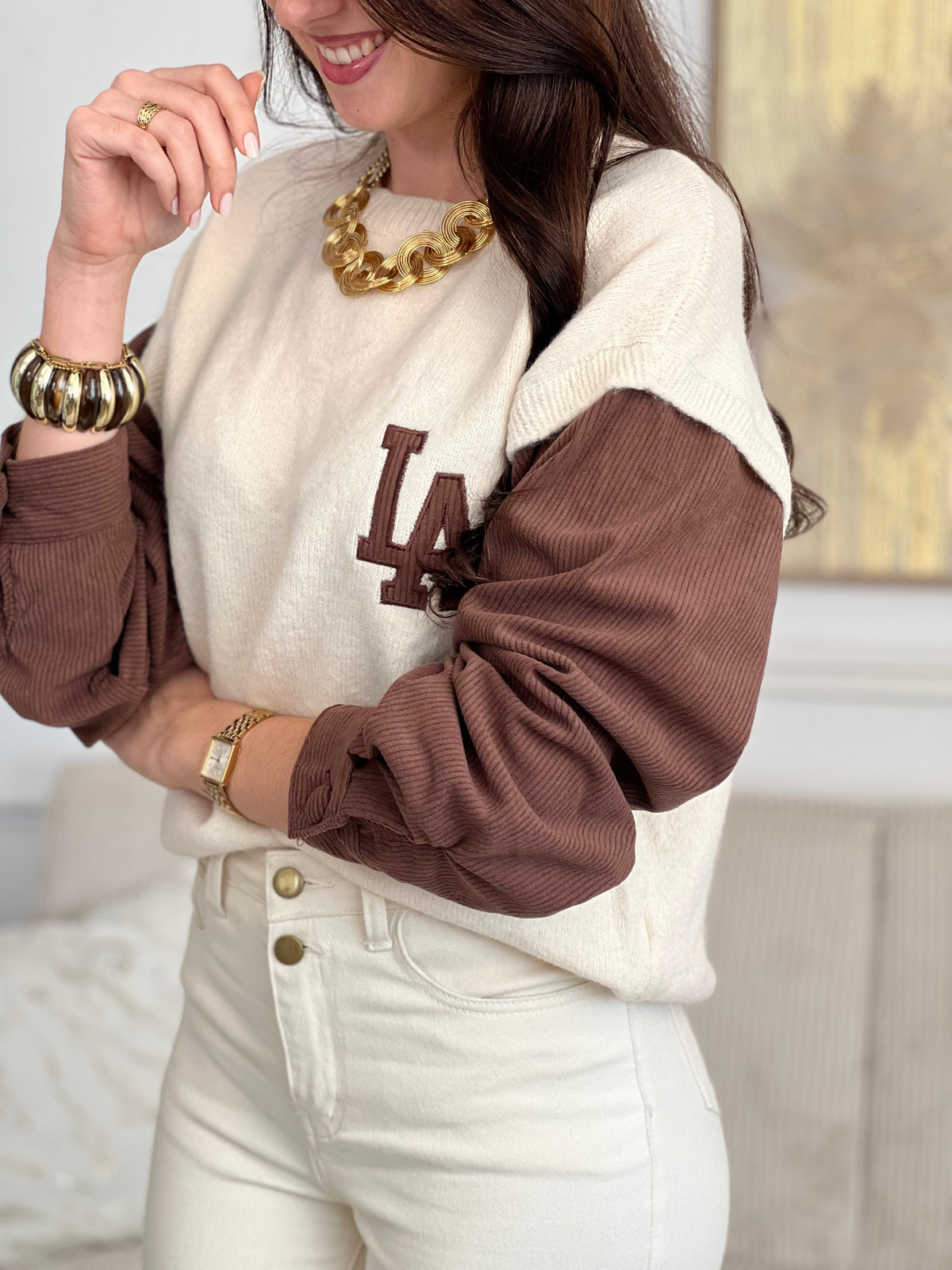 Pull beige et marron aux teintes chaleureuses et apaisantes. Cette pièce bi matière joue sur les contrastes de textures pour un rendu sophistiqué. Le col rond épousant délicatement vos épaules offre une allure intemporelle, tandis que les boutons aux manches ajoutent une touche de détail raffiné.