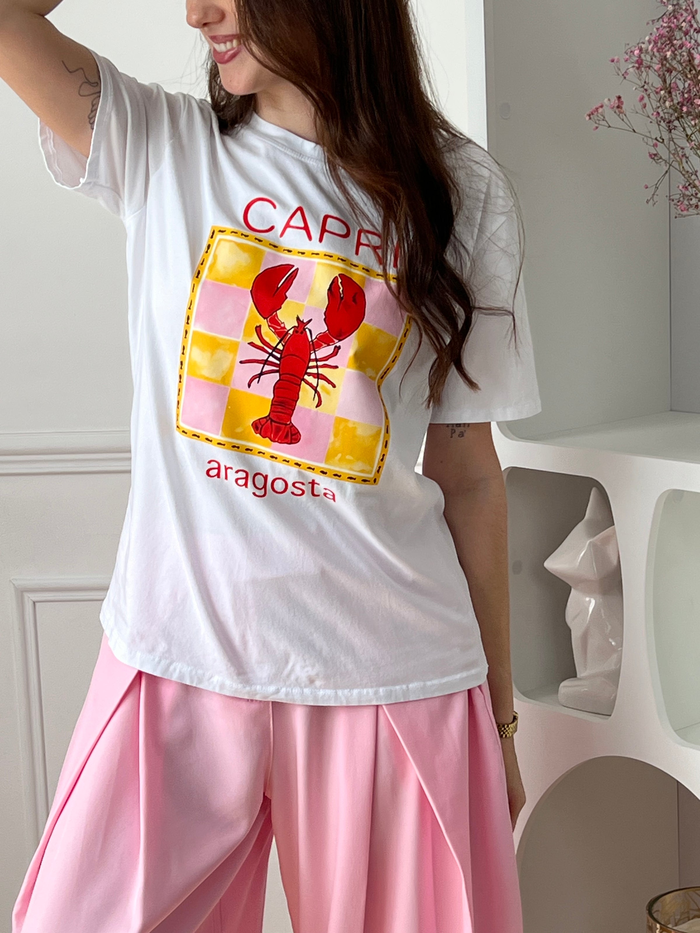 Craquez pour ce top écru femme, original et plein de caractère. Doté de manches courtes et d’un col rond, il se distingue par son illustration de homard accompagnée de motifs jaunes et roses et de l’inscription “Capri Aragosta” en rouge. Une pièce idéale pour un look estival et tendance.