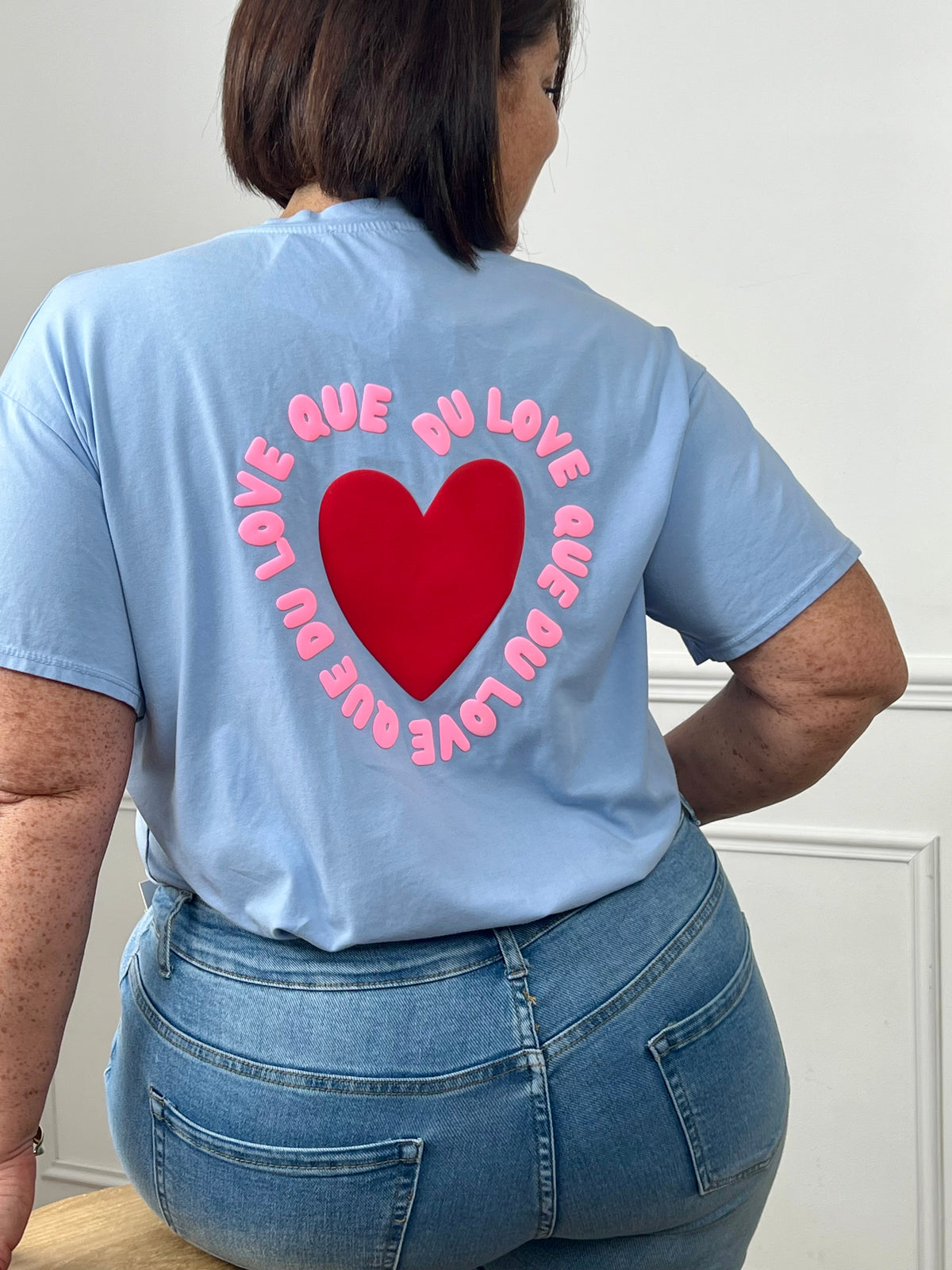 Tee-shirt bleu ciel avec inscription "Que du love" à l’avant et au dos, accompagné d’un cœur pour une touche tendance et positive. Doté de manches courtes et d’un col V, il allie confort et style au quotidien. Ses nuances de bleu, rose et rouge apportent une note fraîche et féminine.