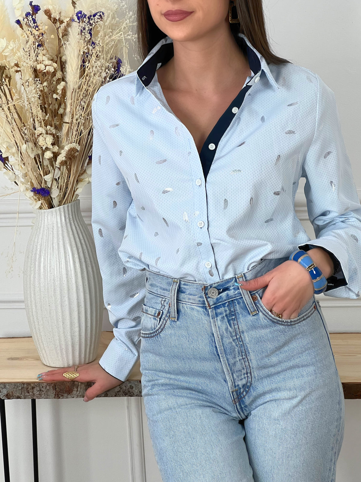 CHEMISE BLEUE A DETAILS ARGENTES FEMME Chemise manches longues Motifs plumes argentées Col chemise Boutons écrus sur la longueur et aux poignets Couleurs : bleu clair et bleu marine sur la longueur des boutons, aux poignets et haut du dos interne Composition : 55% polyester 45% Coton Lavage à la main obligatoire Fabriqué en R.P.C